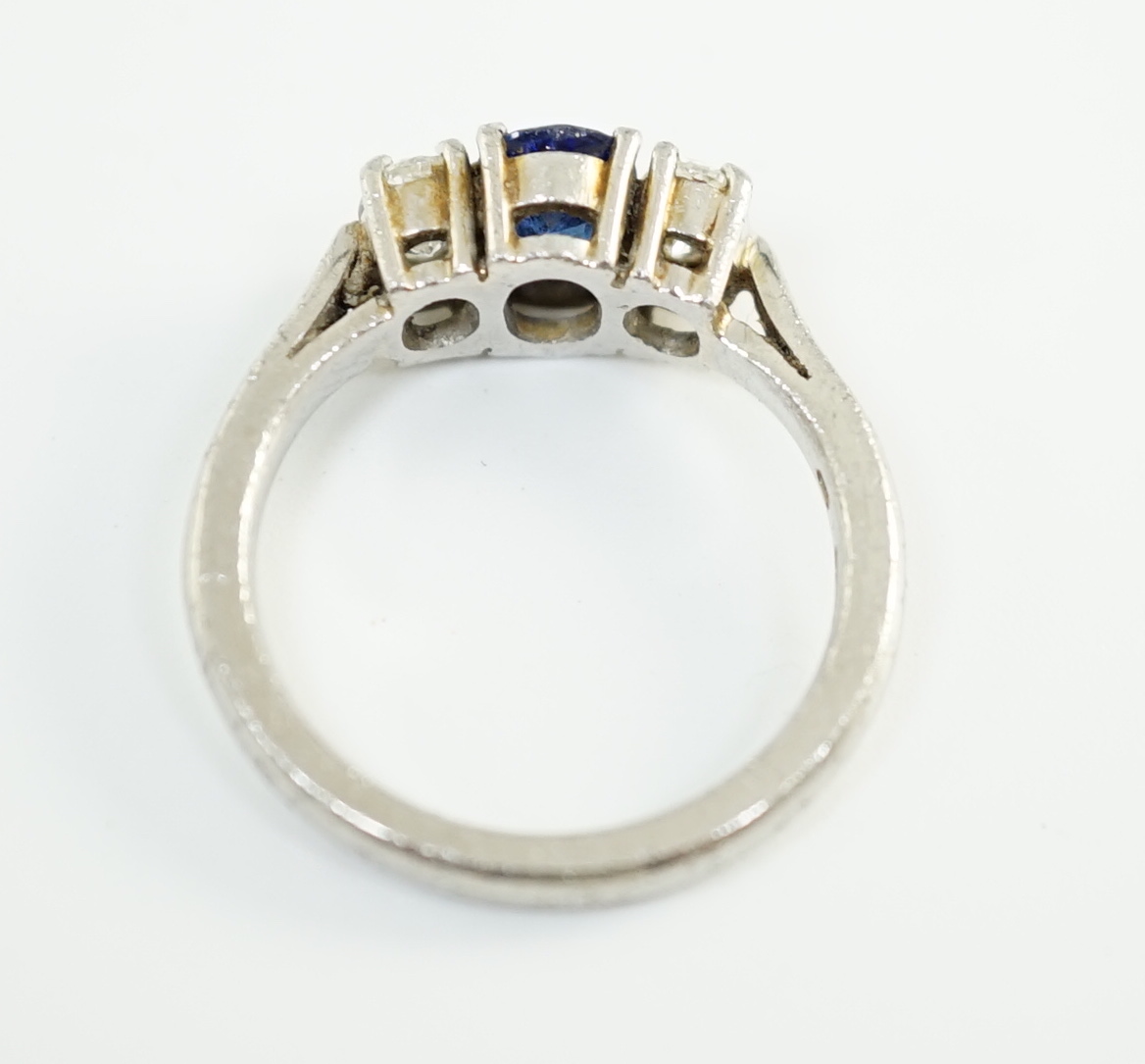 A modern platinum, singe stone oval cut sapphire and two stone oval cut diamond set ring